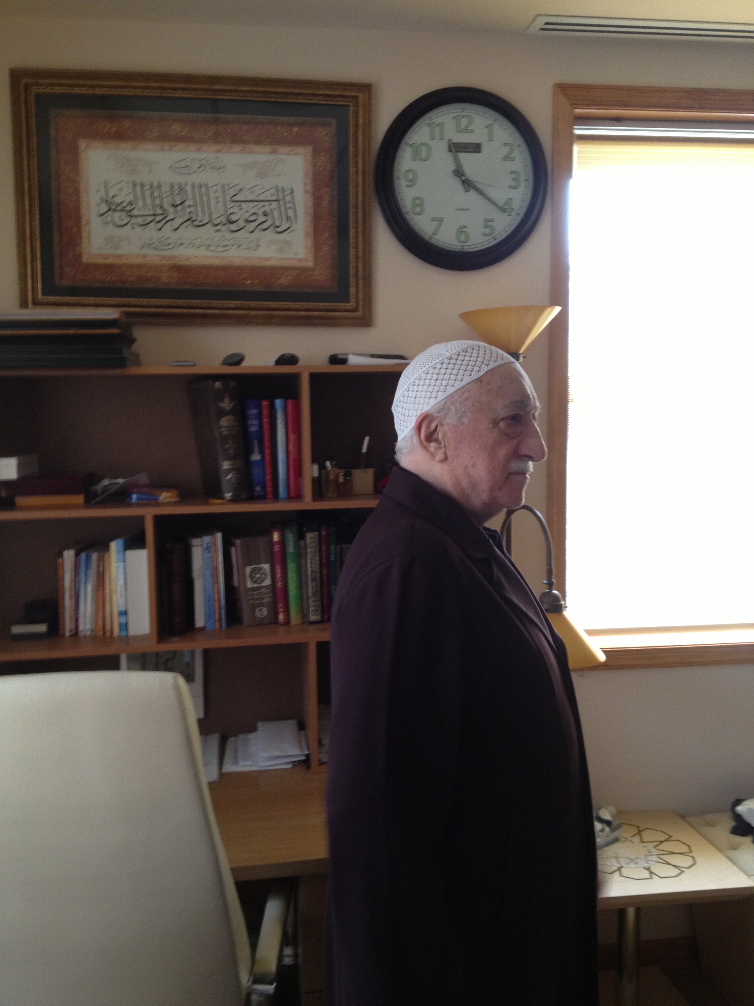 Muhterem Fethullah Gülen Hocaefendi odasındaki çalışma masasının ve Kasas Sûresi'nin 85. ayet-i kerimesini ihtiva eden tablonun önünde hat sanatındaki tecrid derinliğini anlatırken